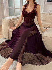 Woman wearing a sheer plum maxi slip dress with floral applique straps sitting on a cream sofa.