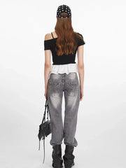 Back view of a woman wearing a black off-the-shoulder top with white ruffle trim and grey jeans.