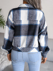 Back view of a woman wearing a blue, white, and black plaid flannel shirt jacket over light wash jeans.