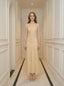 Woman wearing a sleeveless yellow maxi dress with a floral jacquard pattern standing in a hallway.