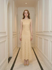 Woman wearing a sleeveless yellow maxi dress with a floral jacquard pattern standing in a hallway.