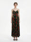 Woman wearing a dark green floral print maxi dress with spaghetti straps and a pleated skirt, front view.