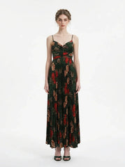Woman wearing a dark green floral print maxi dress with spaghetti straps and a pleated skirt, front view.