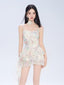 Woman wearing a floral print mini dress with spaghetti straps and a ruffled asymmetrical hem.