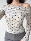 Close-up of a woman wearing a white and grey polka dot off-the-shoulder mesh top