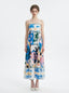 Full front view of a woman wearing a midi dress with an abstract geometric print and spaghetti straps.
