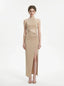 A woman models a shimmering champagne halter neck maxi dress with a cut-out and high slit.