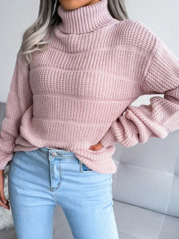 Front view of a woman wearing a pink knit turtleneck sweater with light blue jeans.