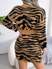 Back view of a woman in a tan and black tiger print knit mini dress with a V-neck and long sleeves.