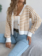 Woman sitting on a sofa wearing a yellow and white striped and checkered knit cardigan