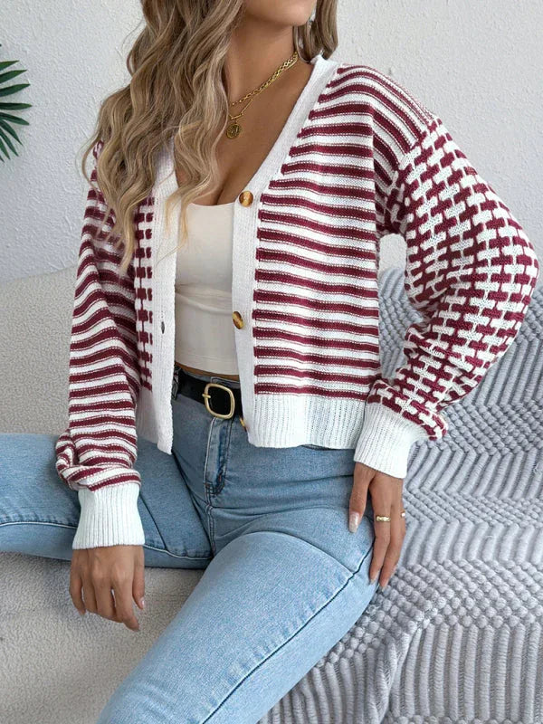 Woman sitting on a sofa wearing a red and white striped and checkered knit cardigan