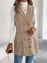Woman wearing a beige corduroy sleeveless blazer over a white turtleneck and blue jeans, holding a coffee cup.