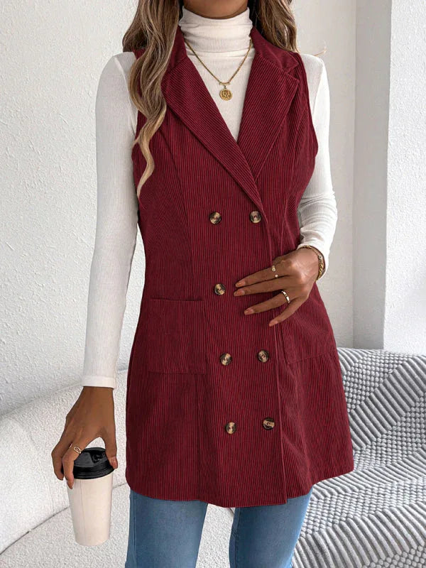 Close-up of a woman wearing a burgundy corduroy sleeveless blazer, holding a coffee cup.