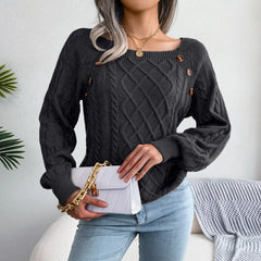 Woman holding a white quilted handbag with a gold chain strap while wearing a charcoal grey cable knit sweater and blue jeans.