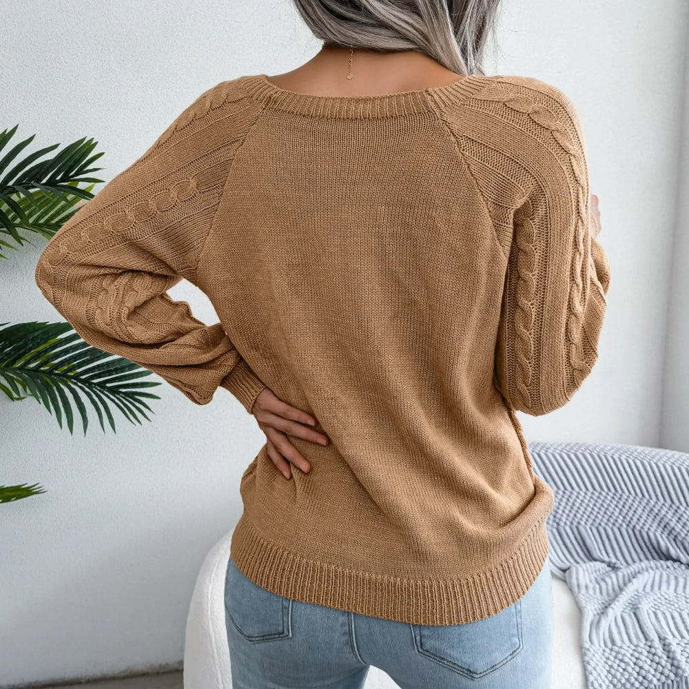 Back view of a woman wearing a tan cable knit sweater with long sleeves and a scoop neck.