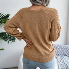 Back view of a woman wearing a tan cable knit sweater with long sleeves and a scoop neck.