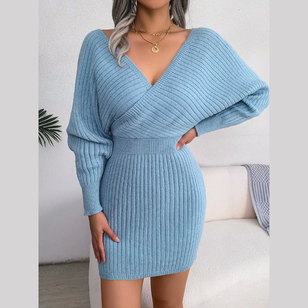 Woman in a light blue knit dress with her hand on her hip, showcasing the V-neckline and long sleeves.
