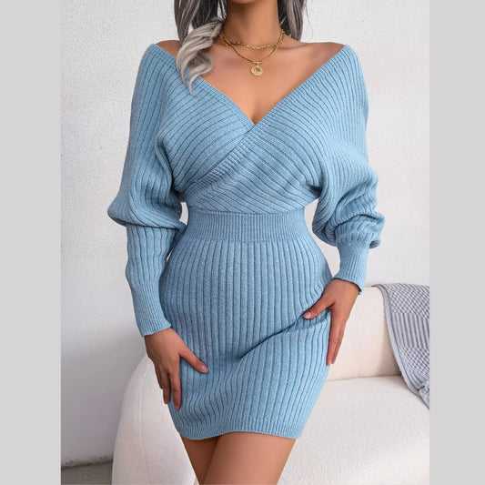 Woman wearing a light blue long-sleeved knit mini dress with a V-neckline and wrap front detail.