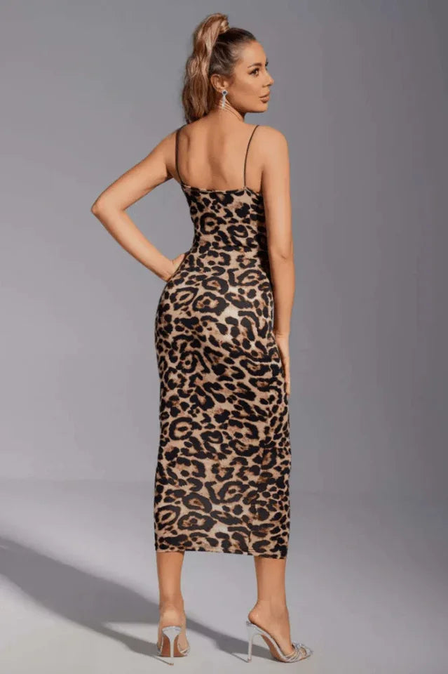 Woman wearing a leopard print bodycon midi dress with spaghetti straps, posing with hands on hips, back view.