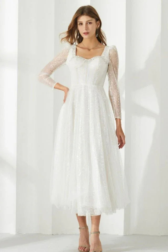 Full-length view of a woman in a white sequined dress with a square neckline and long sleeves.