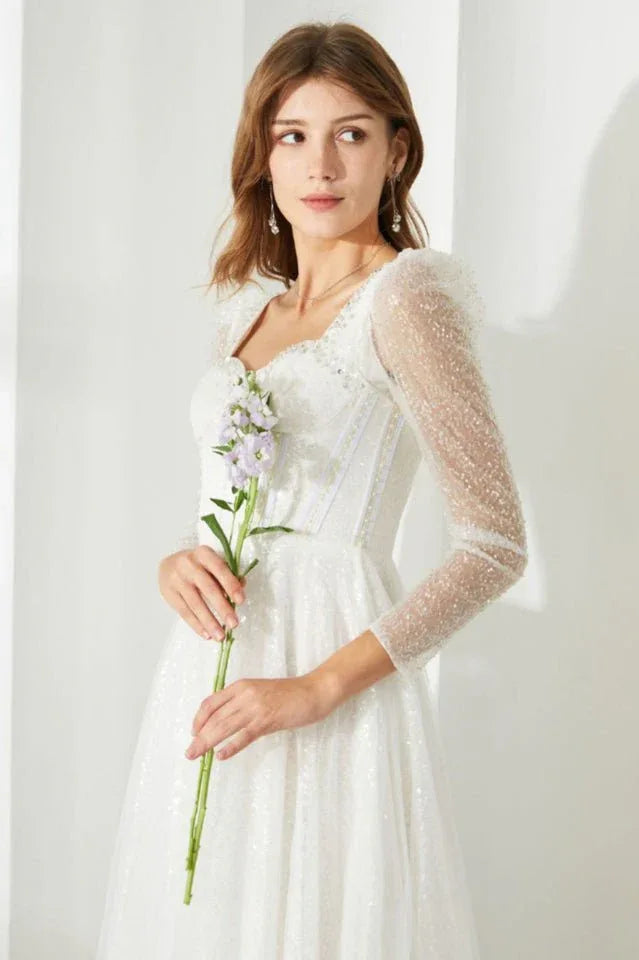 Side view of a woman in a white sequined dress, highlighting the design of the sleeves and neckline.