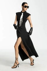 Model in a black sleeveless maxi dress with a white tie detail, showcasing the asymmetrical hemline and slit
