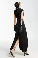 Back view of a model wearing a black sleeveless maxi dress with a high slit and white tie detail