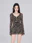 Model wearing a black and gold striped sheer mesh mini dress with a plunging V-neck and long bell sleeves.