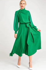 Woman wearing a vibrant green long-sleeved midi dress with a mock neckline and a self-tie belt.