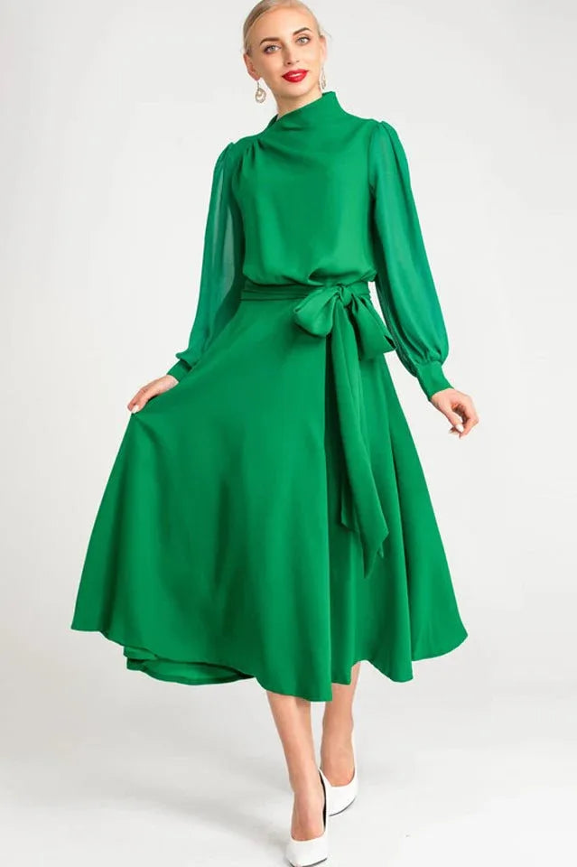 Front view of a woman in a green midi dress with bishop sleeves and a flared skirt.