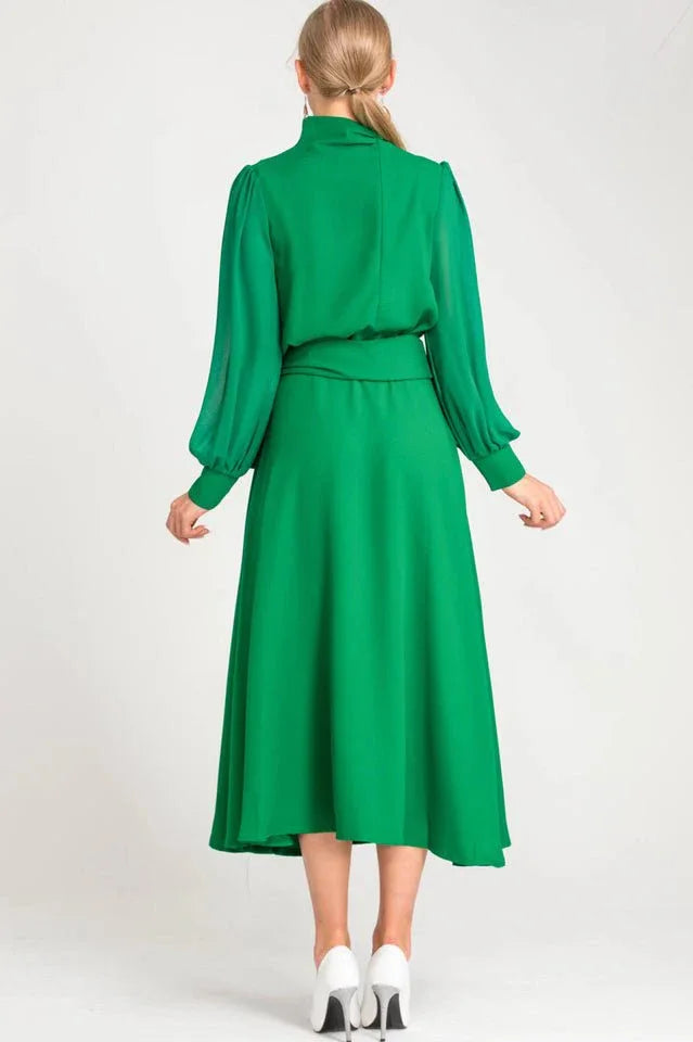 Back view of a woman in a green long-sleeved dress with a midi-length skirt.