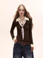 Woman wearing a dark brown fitted knit sweater with a cream collared shirt underneath and a patterned tie, paired with dark wash wide-leg jeans.
