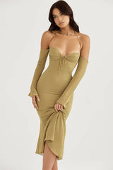 Woman wearing a sage green ruched midi dress with detachable sleeves