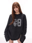 Model wearing a black long sleeve top with a "68" graphic on the front and text on the sleeves.