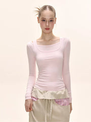 Close-up of a model wearing a pink long-sleeved square neck top and a beige maxi skirt.