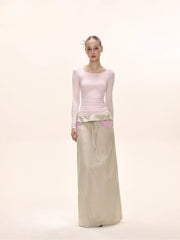 Full body shot of a model in a pink long-sleeved square neck top and a beige maxi skirt.