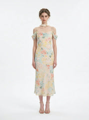 Woman wearing a floral print midi slip dress with off-the-shoulder sleeves and a cowl neckline, standing against a white background.