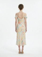 Back view of a woman wearing a floral print midi slip dress with off-the-shoulder sleeves and a cowl neckline, standing against a white background.