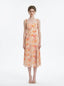 Model wearing a peach floral print midi dress with spaghetti straps and a thigh-high slit, standing against a white background.