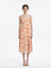 Model wearing a peach floral print midi dress with spaghetti straps and a thigh-high slit, standing against a white background.