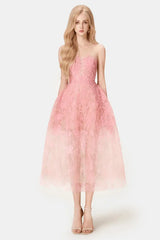 Woman wearing a strapless pink lace midi dress with a full skirt, front view