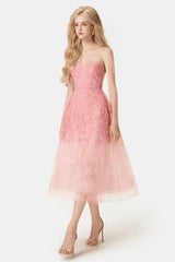 Woman wearing a strapless pink lace midi dress with a full skirt, side view