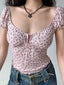Close-up of a woman wearing a pink floral print top with a sweetheart neckline and tie-front detail.
