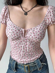 Close-up of a woman wearing a pink floral print top with a sweetheart neckline and tie-front detail.