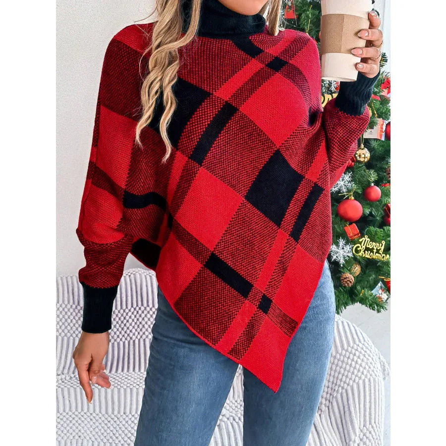 Woman holding a coffee cup while wearing a red and black plaid turtleneck poncho with blue jeans.