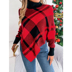 Woman holding a white clutch while wearing a red and black plaid turtleneck poncho with blue jeans.