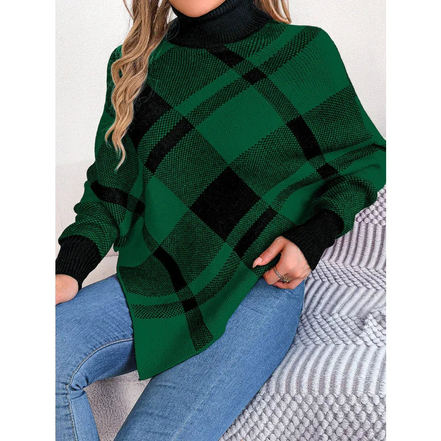 Woman wearing a green and black plaid turtleneck poncho with blue jeans.