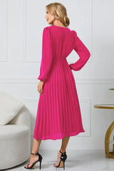 Back view of a woman in a long-sleeved pink wrap dress with a pleated skirt and a self-tie belt