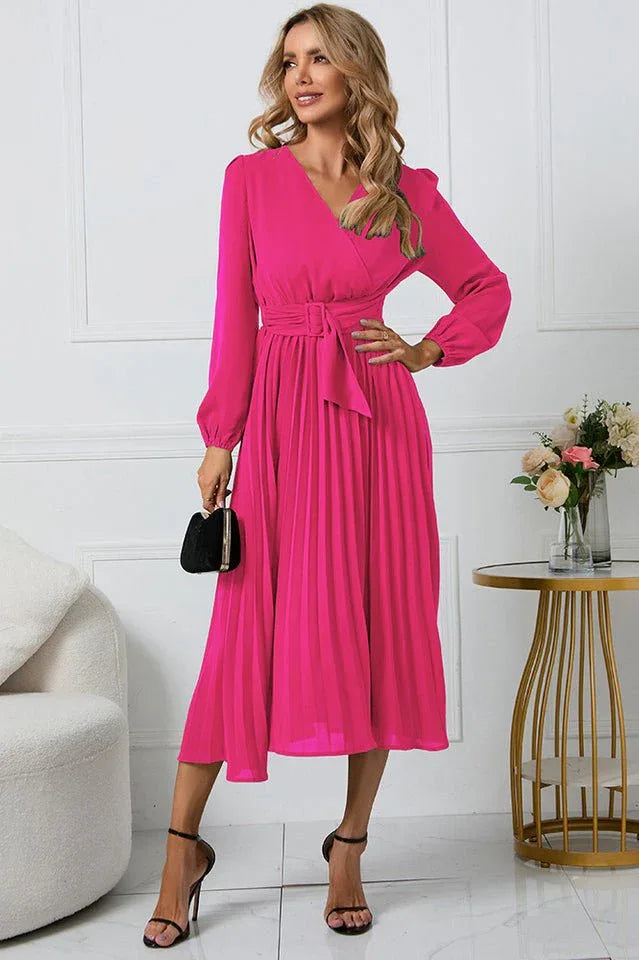Woman wearing a long-sleeved pink wrap dress with a pleated skirt and a self-tie belt