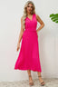 Woman wearing a bright pink sleeveless pleated midi dress with a V-neck and a matching belt